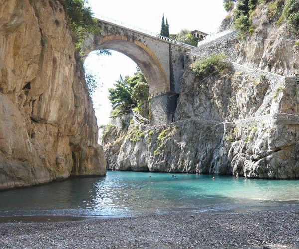 Il ponte ad arco sul Fiordo di Furore, sopra la spiaggetta e l'acqua turchese